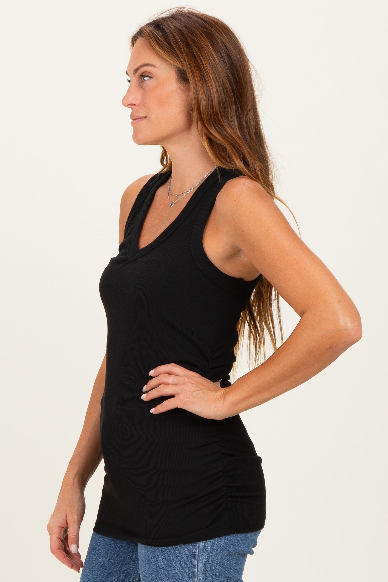 woman wearing a black sleeveless ruched tank top, styled with straight-leg jeans