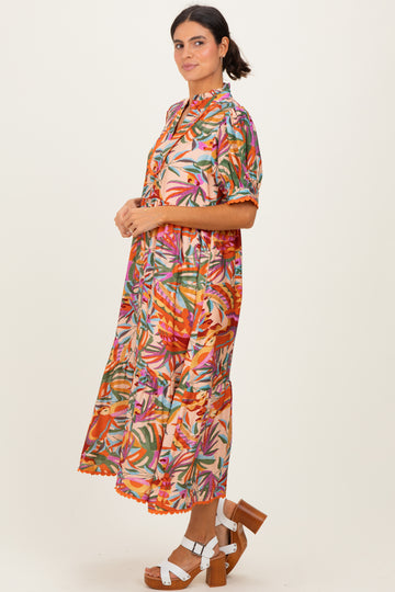 woman wearing a colorful floral midi dress with short sleeves and tiered skirt, paired with brown platform heels