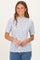 woman wearing a light blue short sleeve floral top with a ruffled neckline and smiling