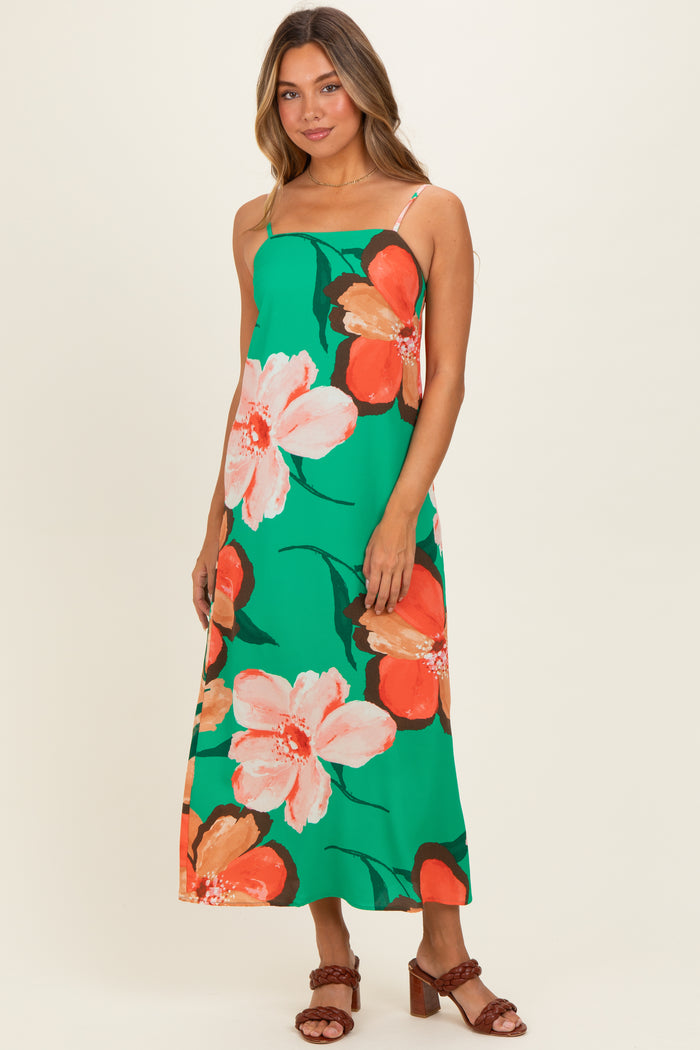woman wearing a green floral maxi dress with orange and white flowers and thin straps