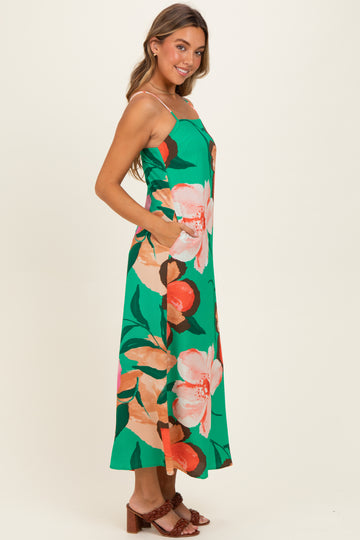 woman wearing a green floral maxi dress with spaghetti straps and side pockets