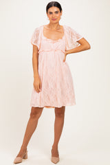 woman wearing a pink lace short dress with flutter sleeves and a fitted waist, paired with nude heels
