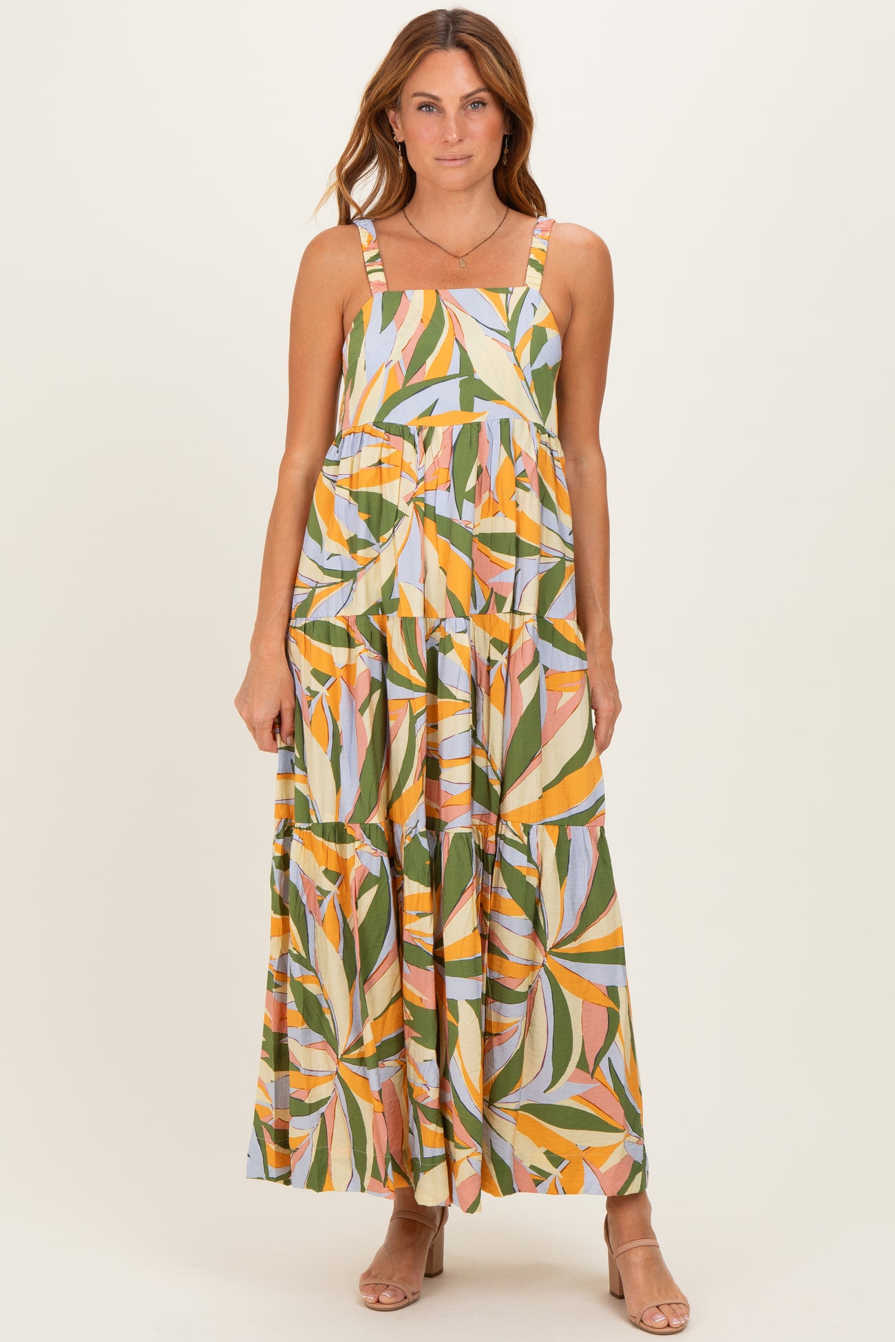 woman wearing a colorful floral print maxi dress with adjustable straps and a tiered design