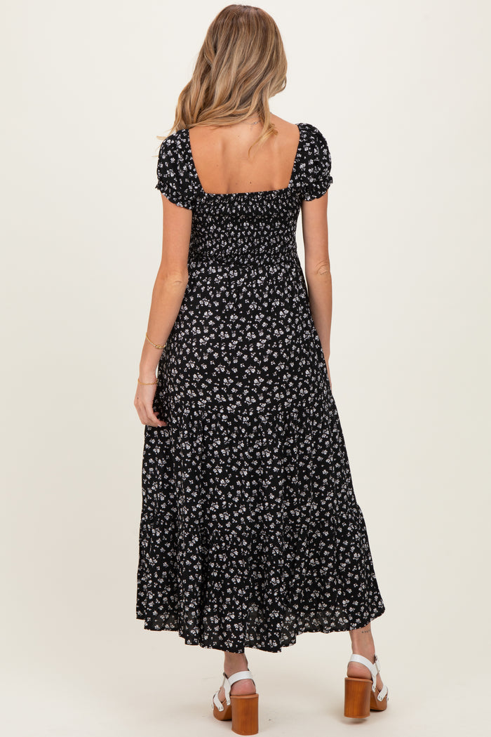 woman wearing a black floral print maternity dress with a square neckline and short puff sleeves