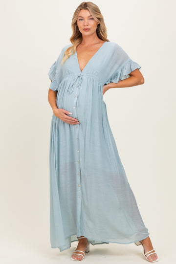 woman wearing a light blue maternity maxi dress with ruffled sleeves and a button-down front, gently holding her baby bump