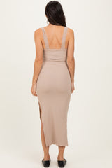 woman wearing a beige ribbed maxi dress with lace details on the straps and a side slit, seen from the back