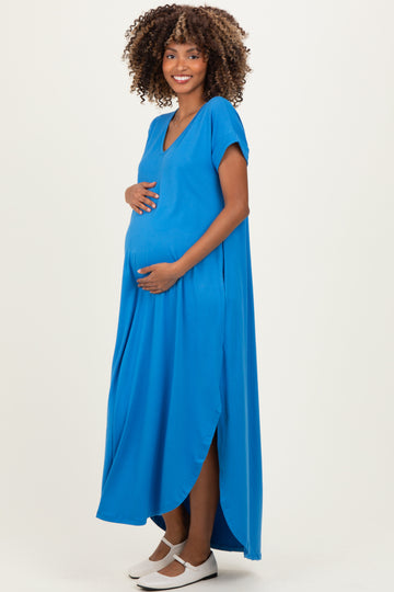 woman wearing a vibrant blue maternity dress with a side slit, gently cradling her baby bump