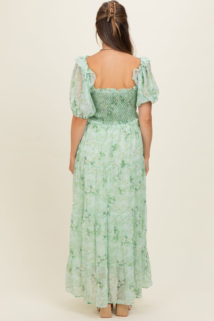 woman wearing a green floral maternity dress with puff sleeves and a smocked bodice, showing the back view