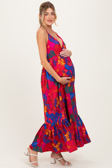 woman wearing a vibrant pink floral maternity maxi dress and cradling her baby bump