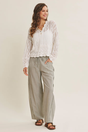 woman wearing a white crochet long sleeve top with a v-neck and wide-leg striped pants