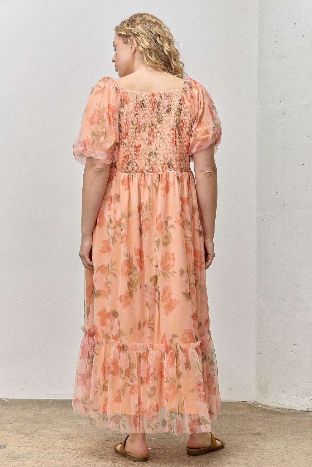 woman wearing a floral print plus-size maxi dress with short puff sleeves and a smocked bodice, view from the back
