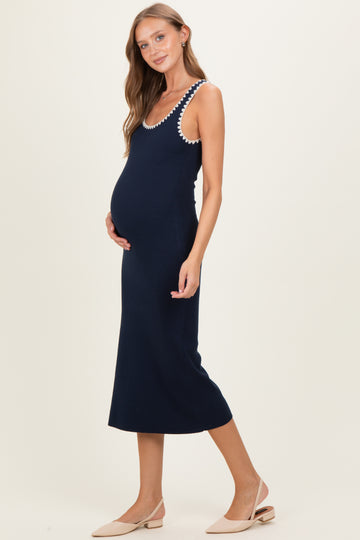 woman wearing a navy blue maternity dress with decorative straps and a visible baby bump