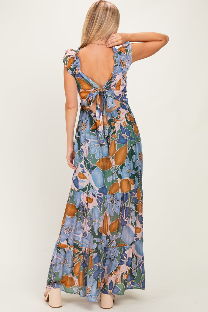 woman wearing a floral maxi dress with ruffle sleeves and an open back tied with a bow