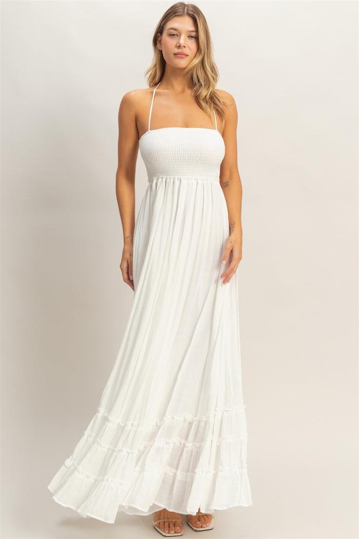 woman wearing a white strapless maxi dress with a smocked bodice and tiered ruffle hem