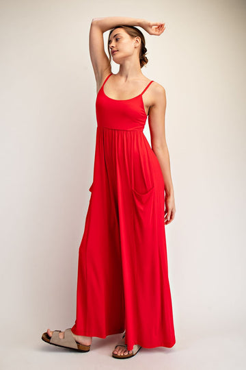 woman wearing a red sleeveless maxi dress with pockets and relaxed fit, posing with one arm raised