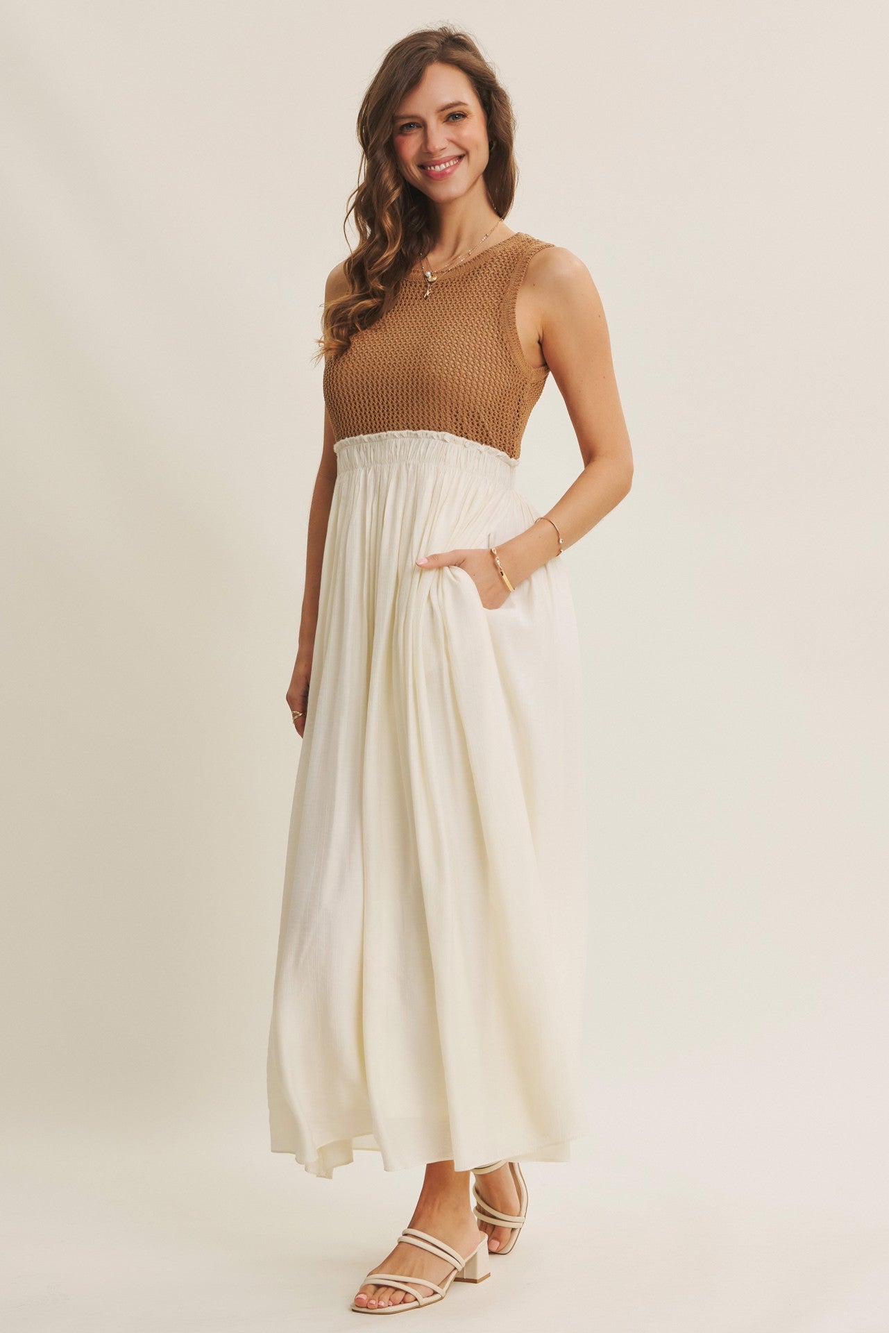 woman wearing a brown knit sleeveless top and a flowy white maxi skirt with pockets