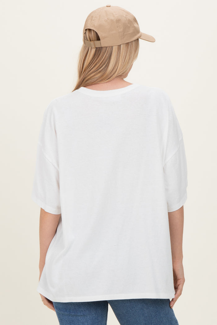 woman wearing a white oversized t-shirt and a beige baseball cap, viewed from the back