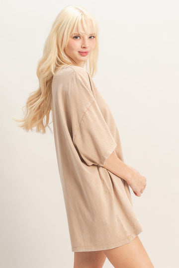 woman wearing a beige oversized t-shirt dress with short sleeves and a relaxed fit