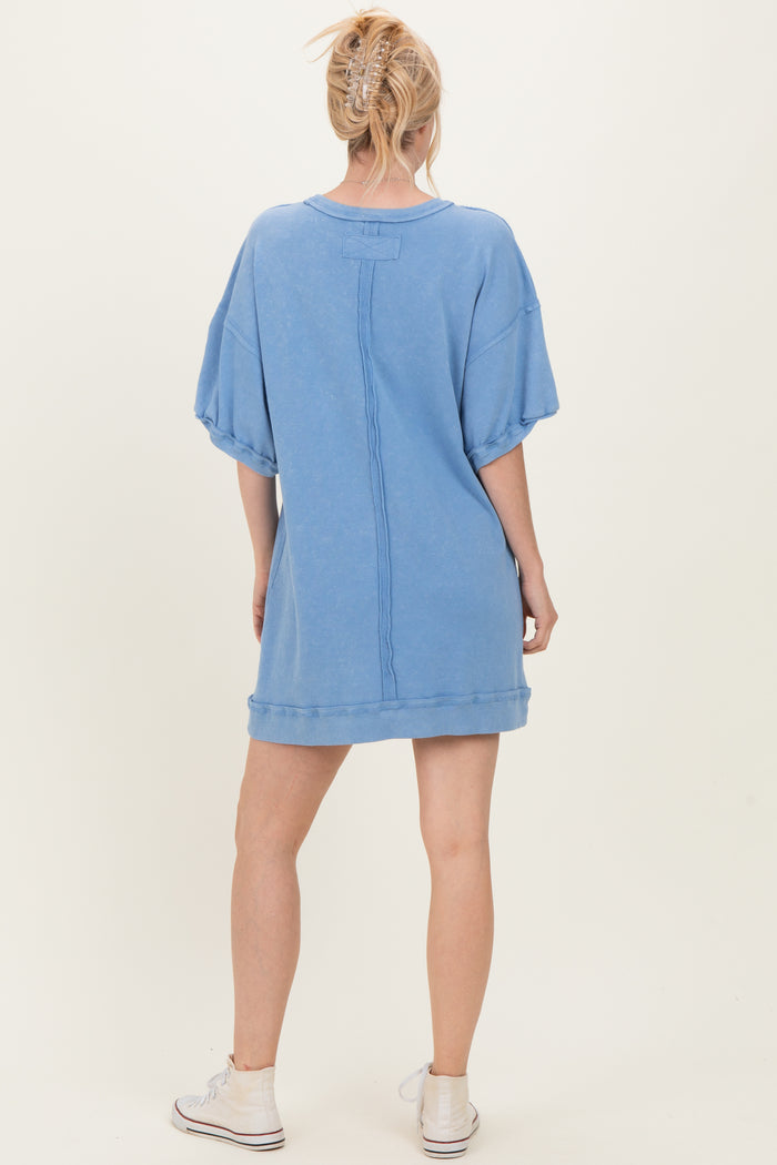woman wearing a light blue oversized sweatshirt dress with short sleeves and a relaxed fit