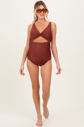 woman wearing a rust-colored maternity swimsuit with a cut-out detail and a baby bump visible