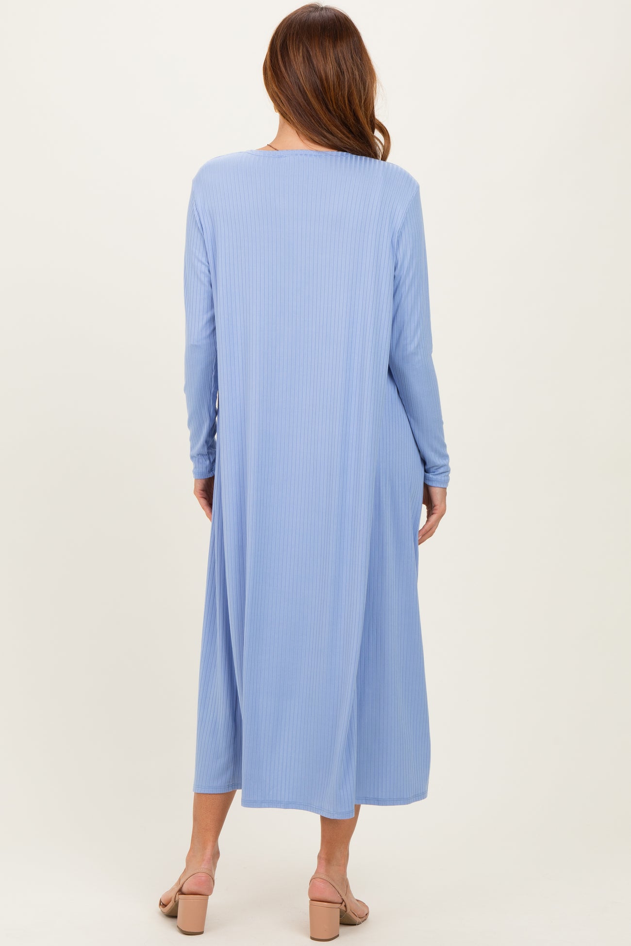 woman wearing a long sleeve blue ribbed maxi dress, viewed from the back, with a flowy silhouette and open back design
