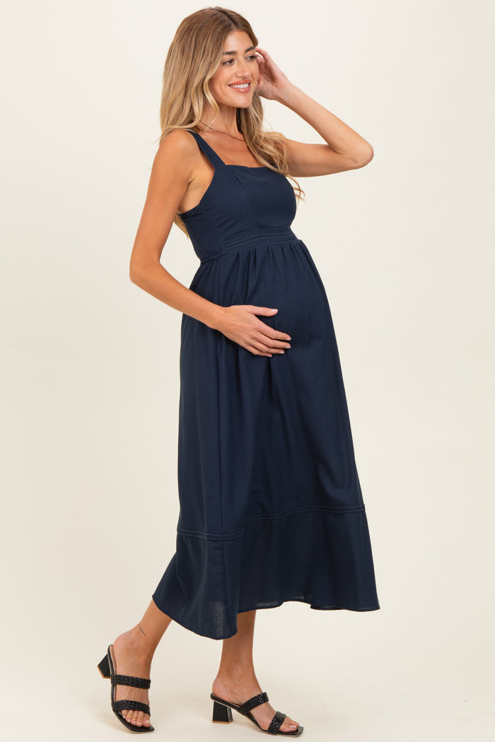 woman wearing a navy blue maternity maxi dress, showcasing her baby bump and styled with sandals