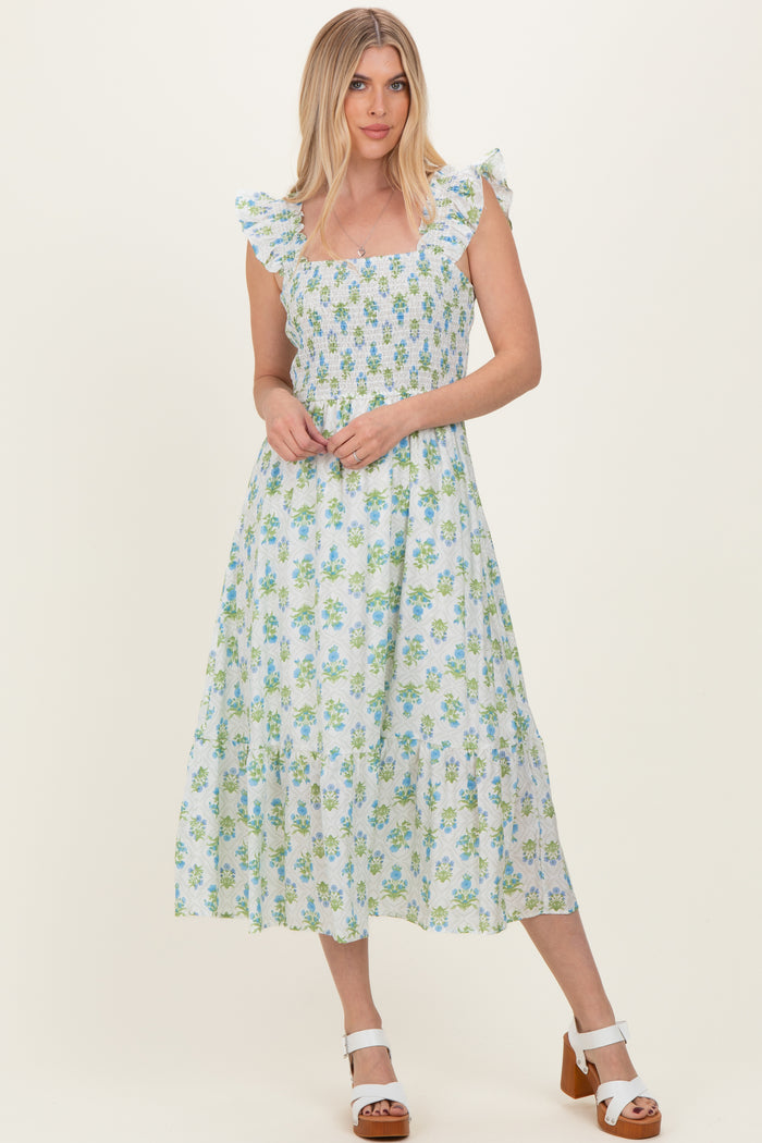 woman wearing a square neckline floral midi dress with ruffle straps in light blue and green colors