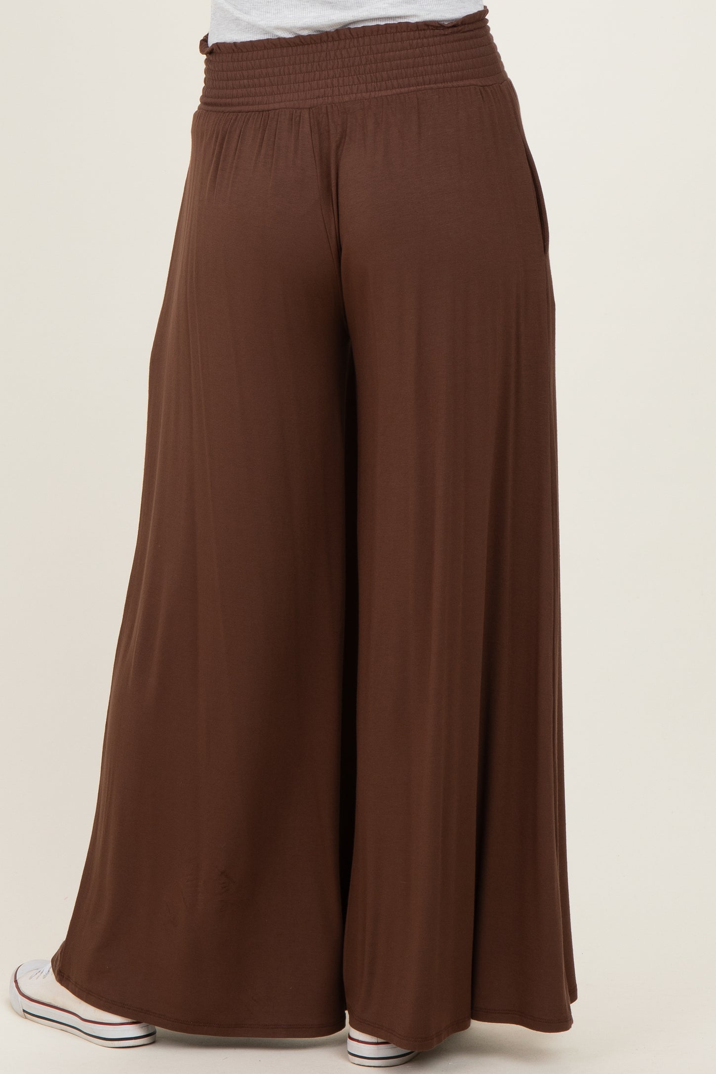 woman wearing brown wide-leg pants with a smocked waistband and a relaxed fit, viewed from the back