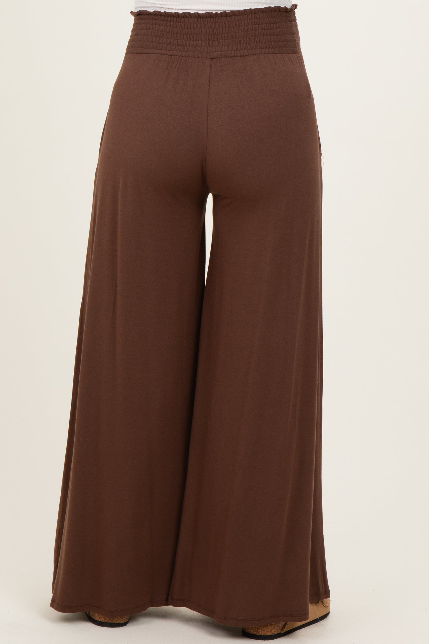 woman wearing brown wide-leg maternity pants with an elastic waistband, viewed from the back
