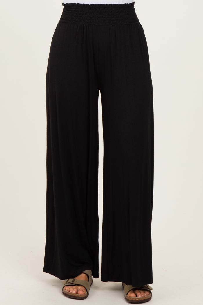 woman wearing black wide leg pants with a smocked waistband and sandals