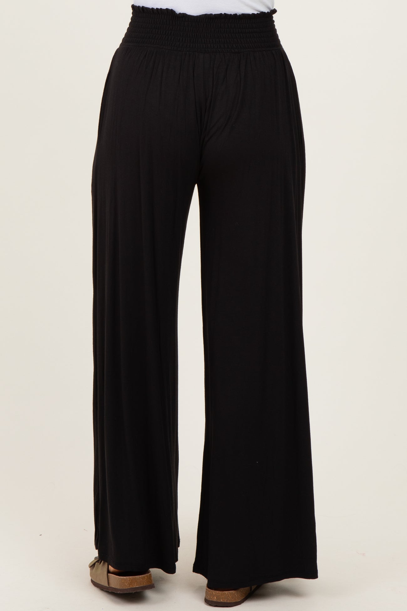 back view of woman wearing black wide-leg pants with smocked waistband and relaxed fit