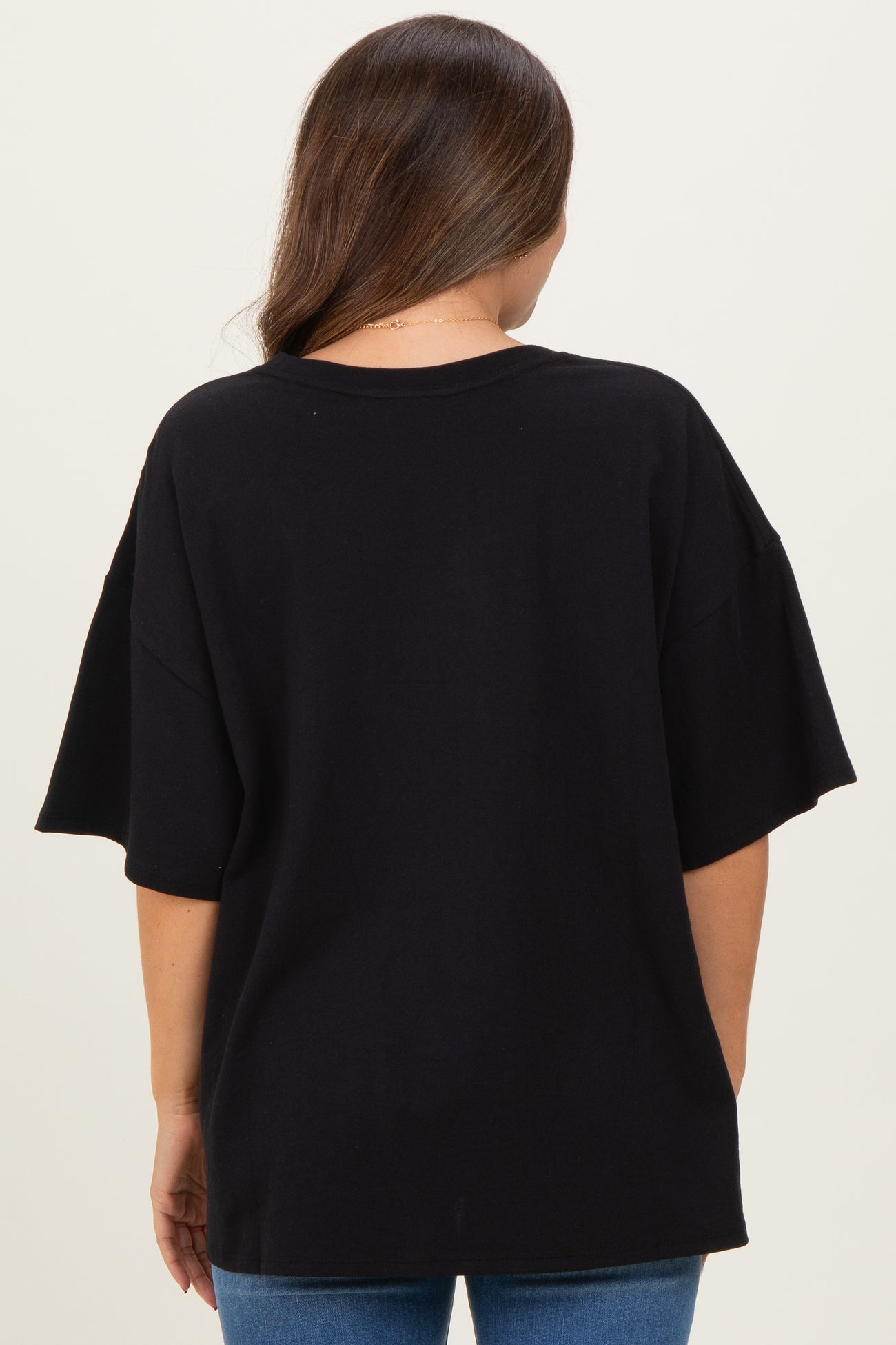 woman wearing a black oversized maternity t-shirt from the back, paired with blue jeans