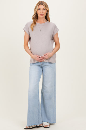 woman wearing a light gray short sleeve maternity top and light blue wide leg jeans with her baby bump visible
