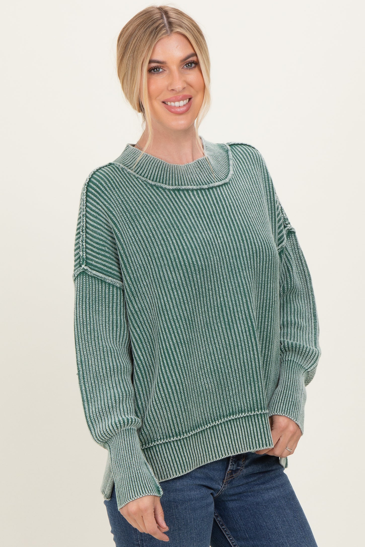 woman wearing a green striped oversized sweater and blue jeans