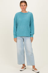 woman wearing a teal oversized ribbed sweater and light wash wide leg jeans with white slip-on shoes