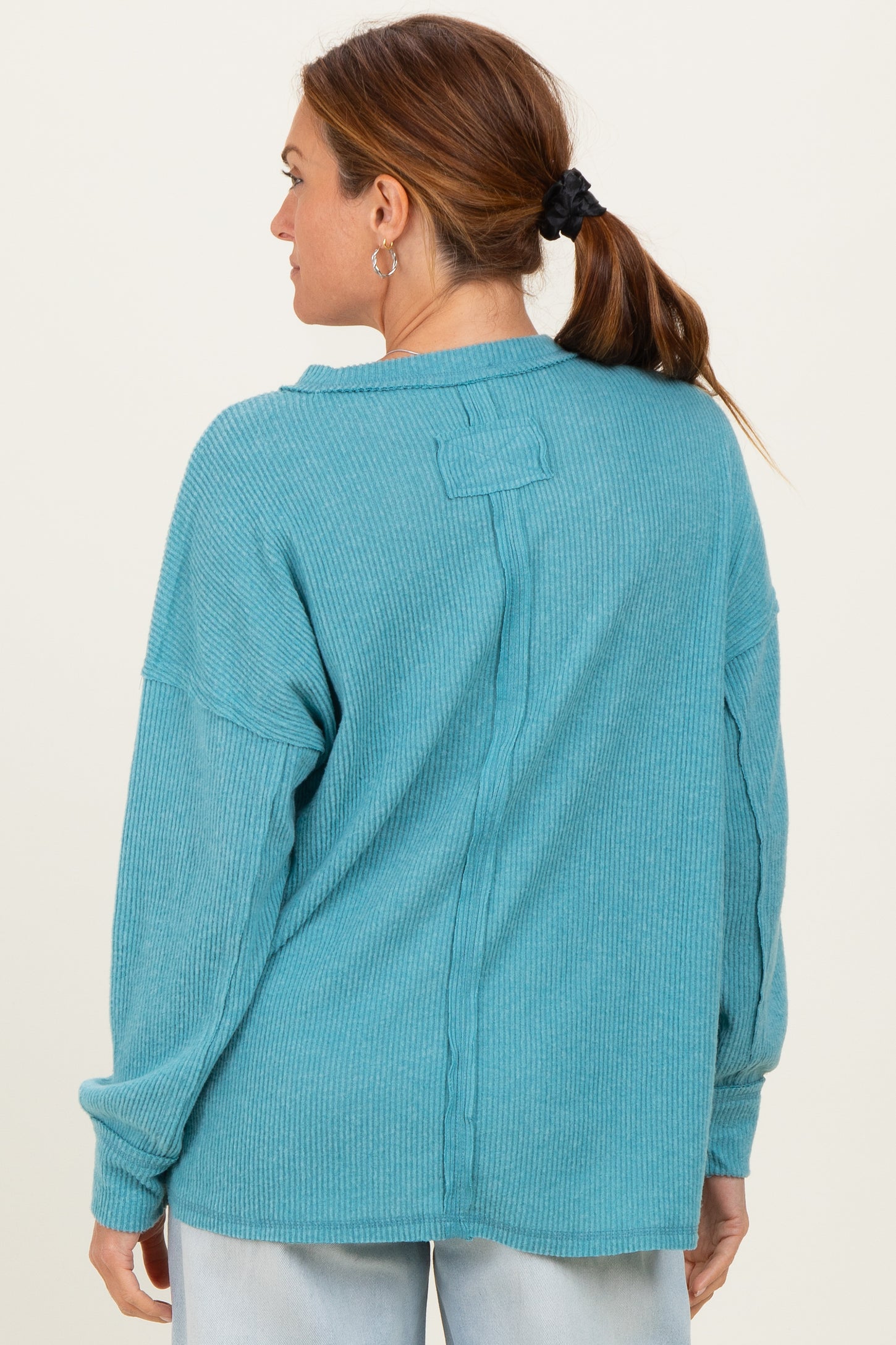 woman wearing a teal ribbed long sleeve top with a relaxed fit and back seam detail