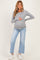 woman wearing a gray long sleeve maternity top and holding her baby bump with light blue distressed cropped jeans