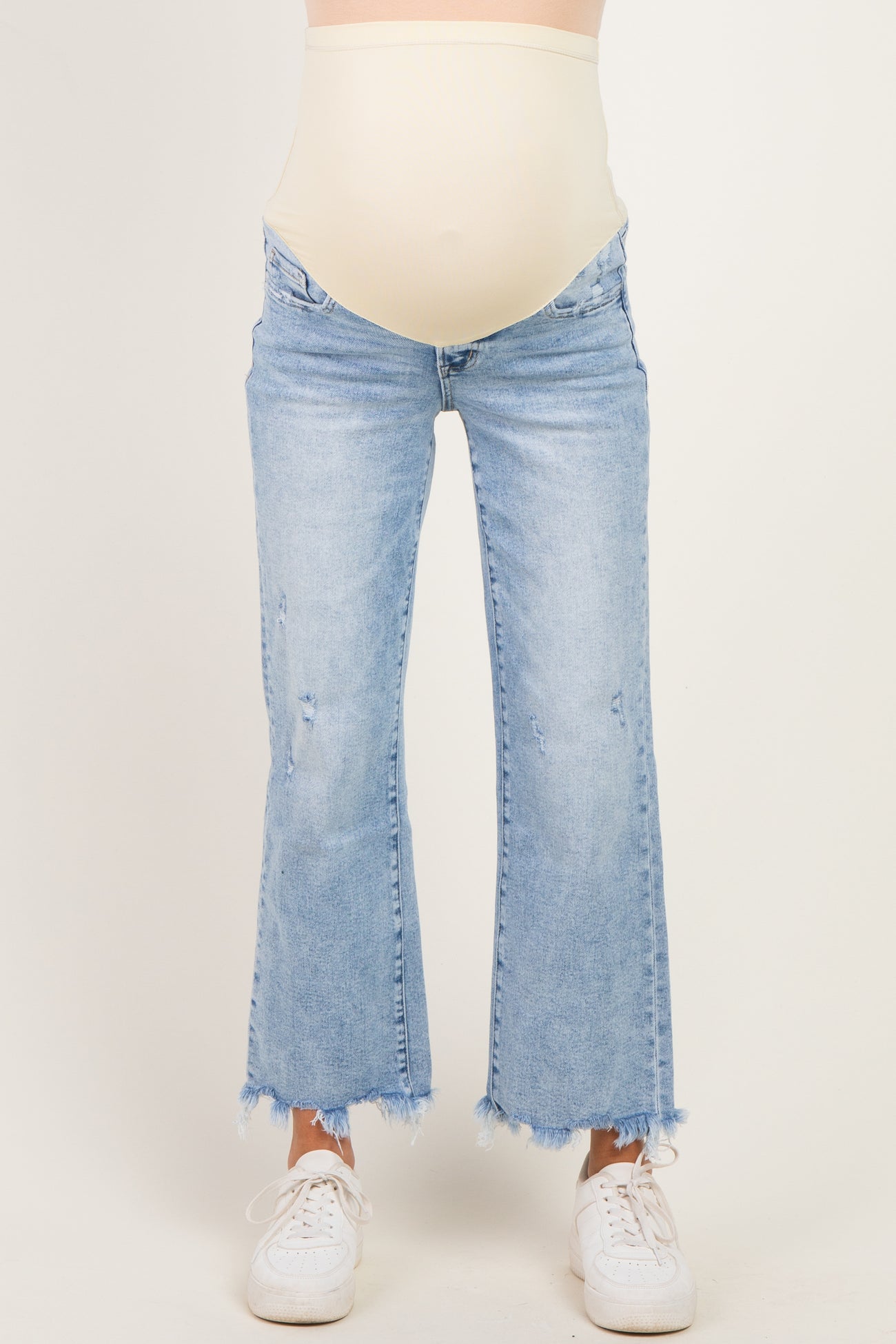 woman wearing light blue maternity flared jeans with a raw hem and a beige over-the-bump waistband