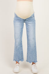 woman wearing light blue maternity flared jeans with a raw hem and a beige over-the-bump waistband