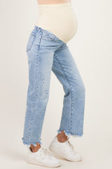 woman wearing light blue distressed maternity jeans with a beige belly support band and white sneakers