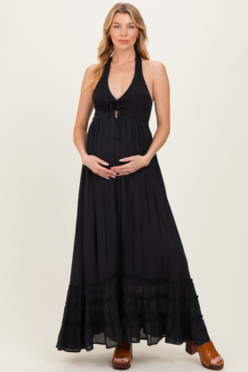 woman wearing a black halter maxi maternity dress and holding her baby bump