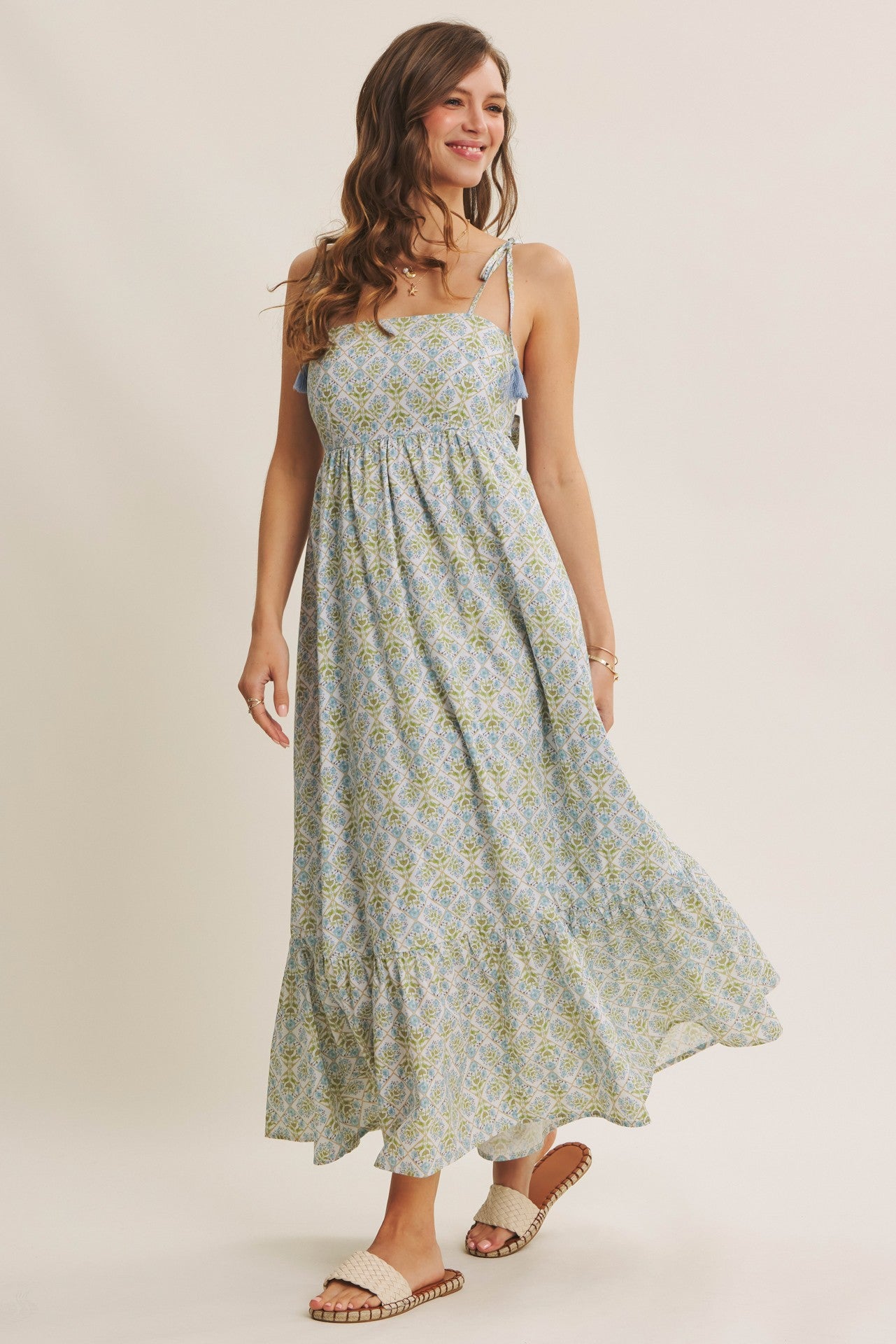 woman wearing a light blue floral maxi dress with spaghetti straps and a tiered skirt