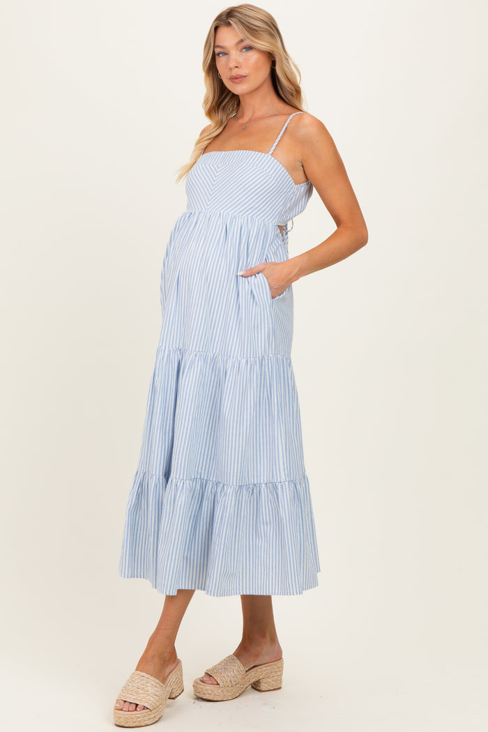 woman wearing a light blue striped maternity maxi dress with pockets and spaghetti straps, showcasing her baby bump