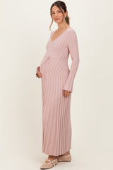 woman wearing a blush pink long sleeve ribbed maternity dress with a tie waist and visible baby bump