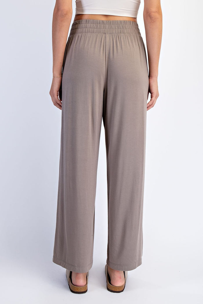 woman wearing light brown wide-leg pants with an elastic waistband, viewed from the back