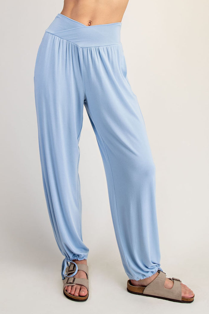 woman wearing light blue relaxed-fit pants with a wide waistband and gathered hems, paired with sandals