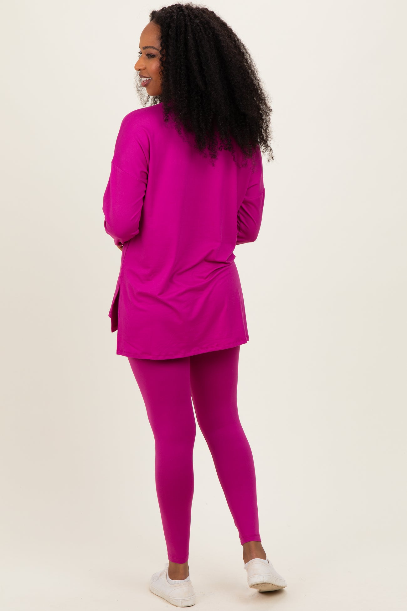 woman wearing a bright pink long sleeve tunic and matching leggings, seen from the back