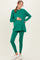 woman wearing a green maternity top and matching leggings, holding her baby bump