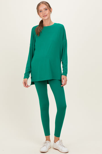 woman wearing a green maternity top and matching leggings, showing a visible baby bump, styled with white sneakers