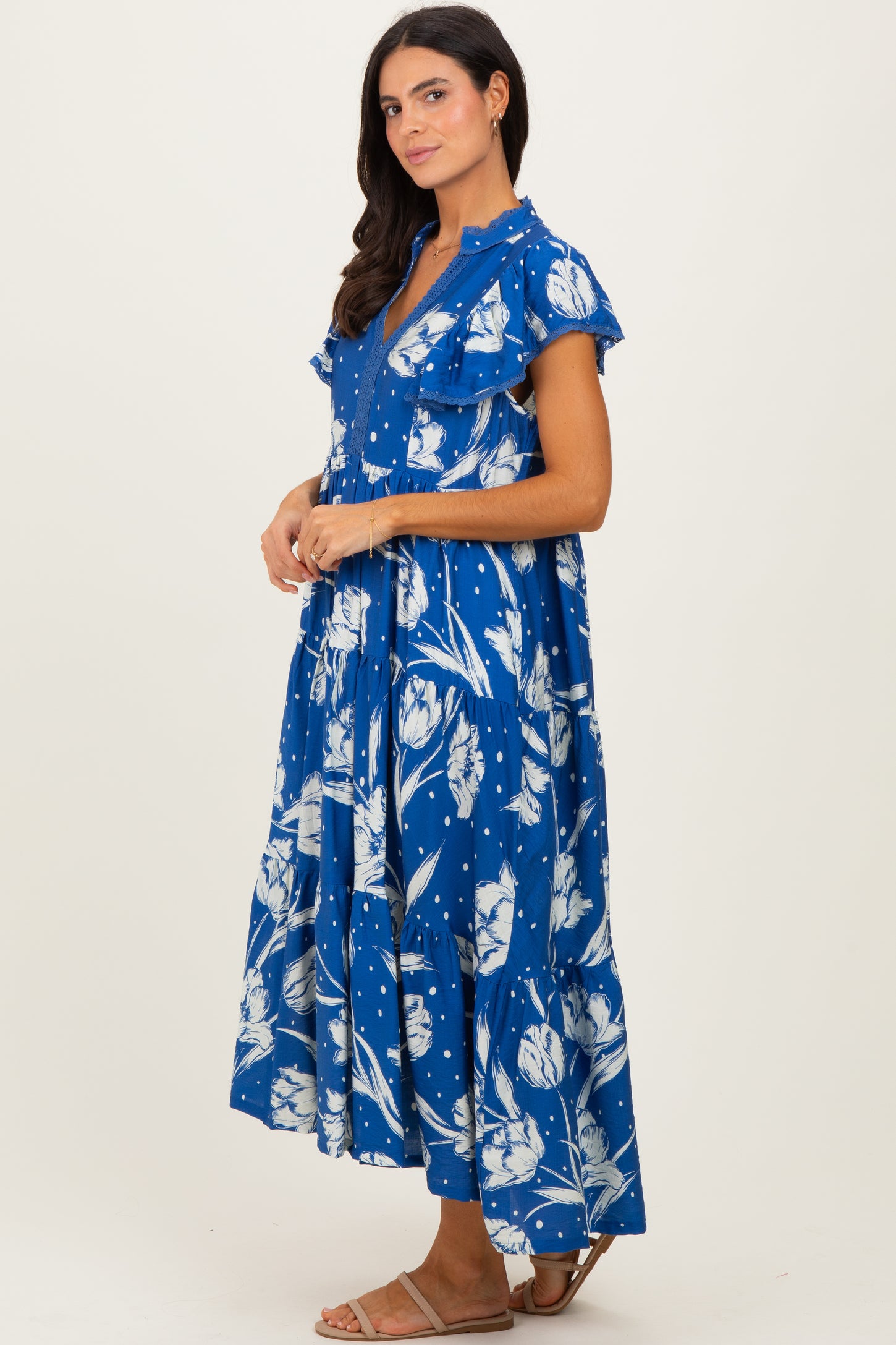 woman wearing a blue floral maxi dress with ruffle sleeves and a tiered skirt